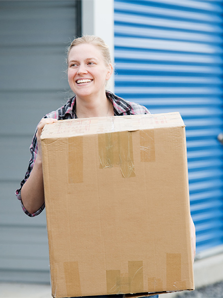 Woman with a box in front of a storage facility